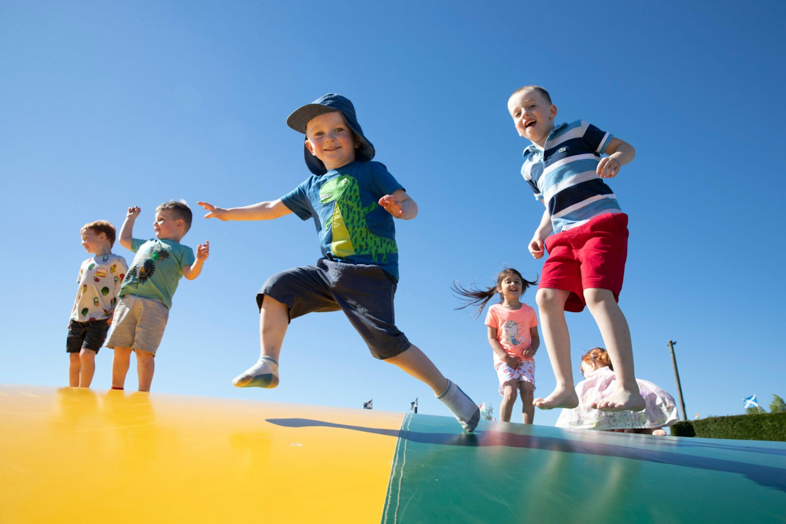 Children bouncing on an inflatable trampoline pillow at an outdoor petting farm adventure centre in Liverpool during autumn family day out