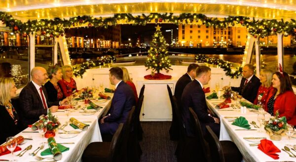 Festive dinner on the deck of the Floating Grace boat restaurant, which is decorated with Christmas garlands, lights, and a tree, overlooking the Albert Dock.